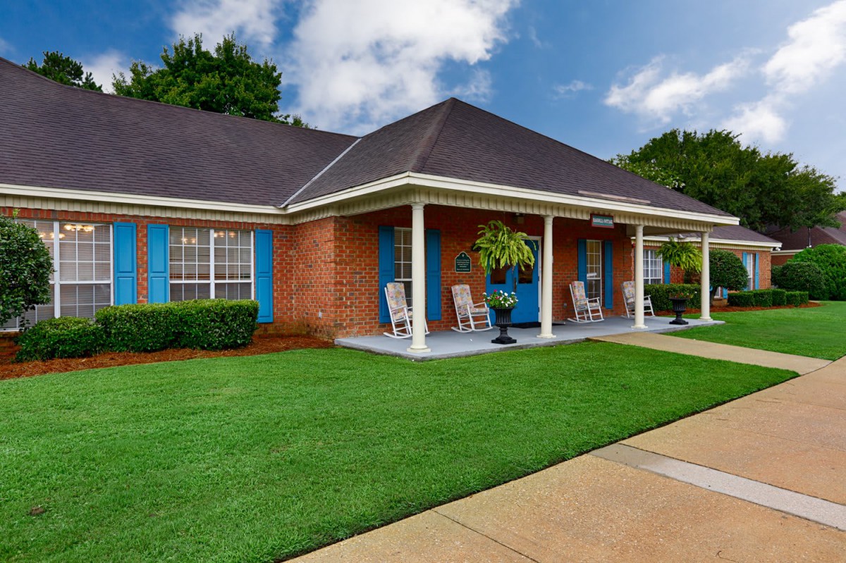 A charming brick house with a welcoming front porch and well-maintained lawn.