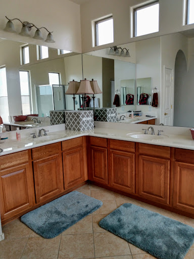 A spacious and well-lit bathroom featuring dual vanities, wooden cabinetry, and decorative mirrors.