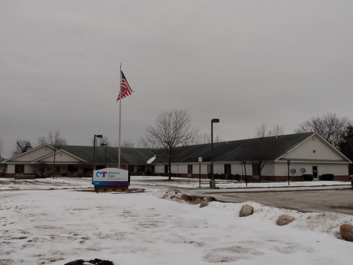 A building with an American flag in a snowy parking lot on a cloudy day.
