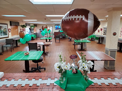 A festive setup for a football-themed party, featuring green tables, balloons, and floral arrangements.