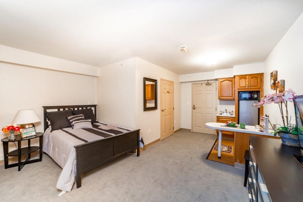 A cozy studio apartment featuring a bedroom area and kitchenette.
