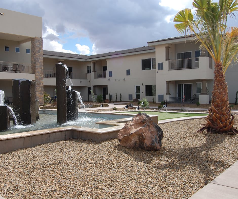 A courtyard with a fountain and landscaping in an apartment complex.