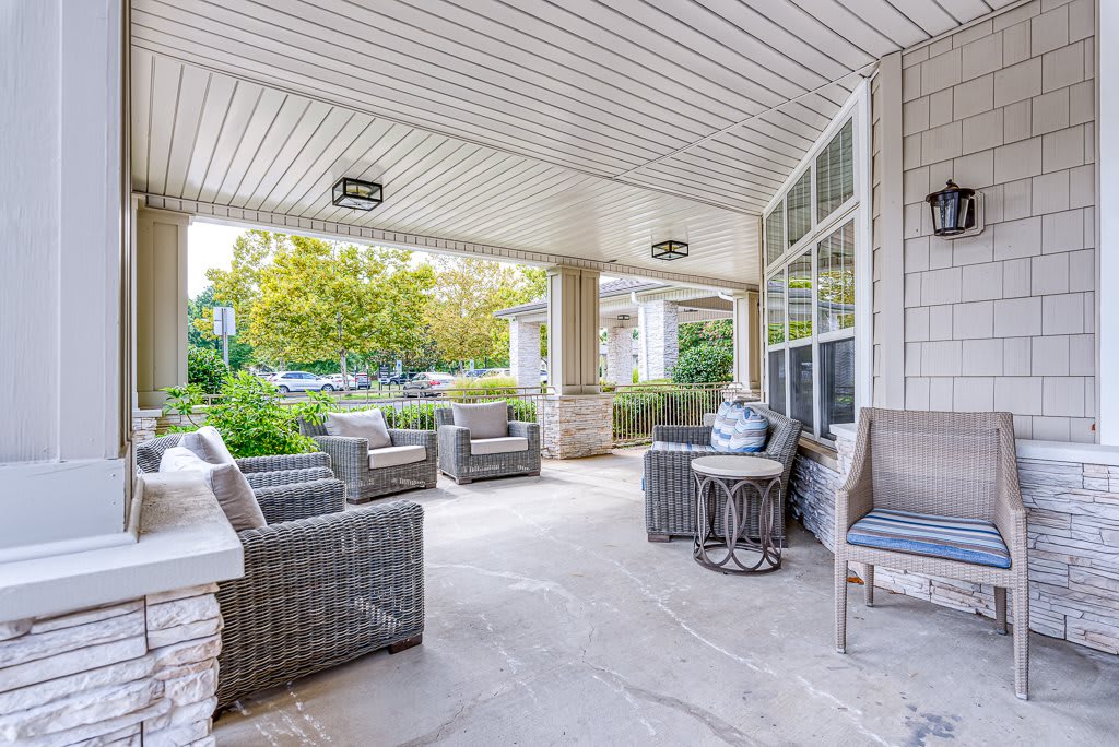 A cozy covered porch with wicker furniture offering a serene garden view.