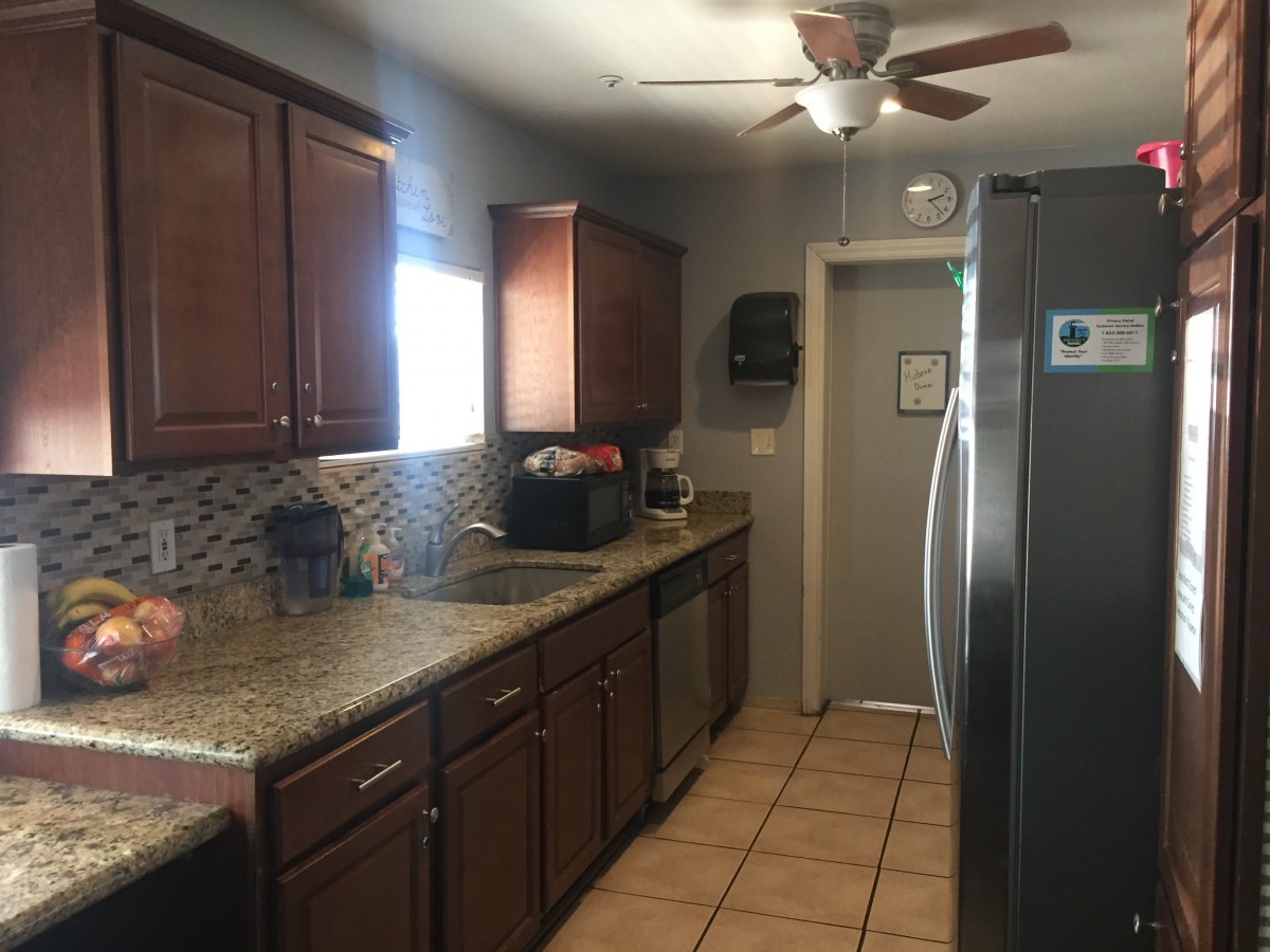 A modern kitchen with dark wooden cabinets, a granite countertop, and stainless steel appliances.