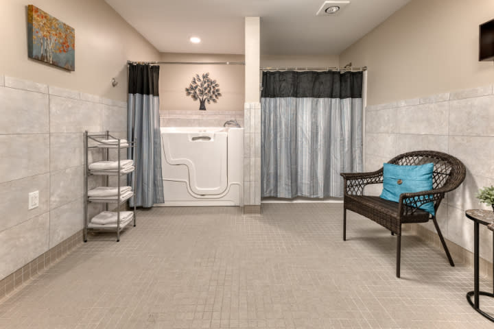 A spacious bathroom featuring a walk-in tub with surrounding curtains and neatly stacked towels.