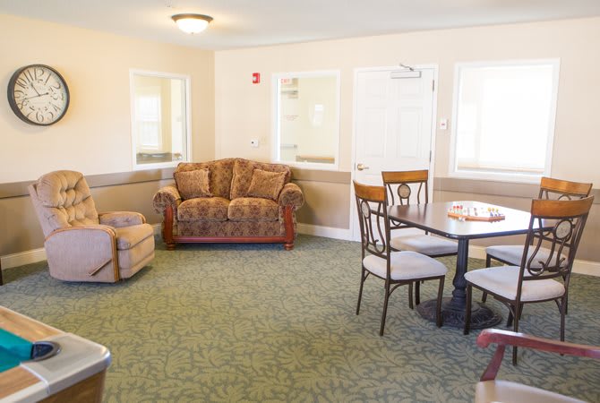 A cozy living room with a sofa, chairs, and a table on a carpeted floor.