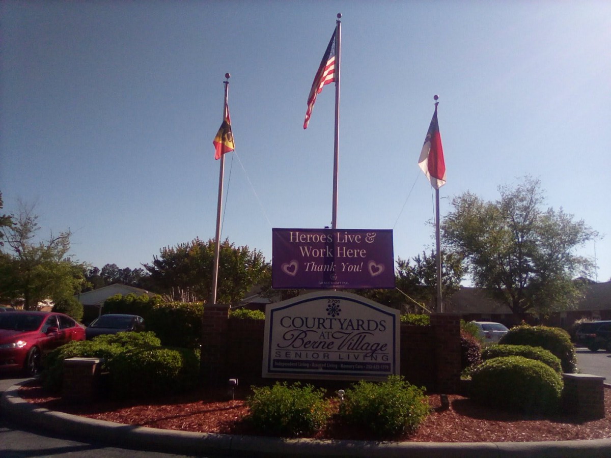 An outdoor view of a school's entrance sign with flags and landscaping.
