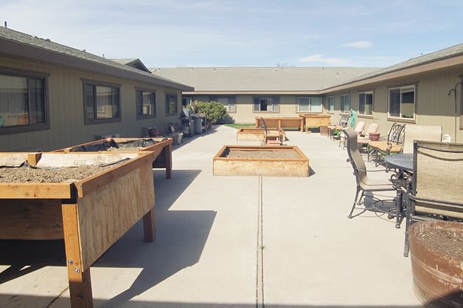 A spacious outdoor courtyard with tables, chairs, and benches on a sunny day.