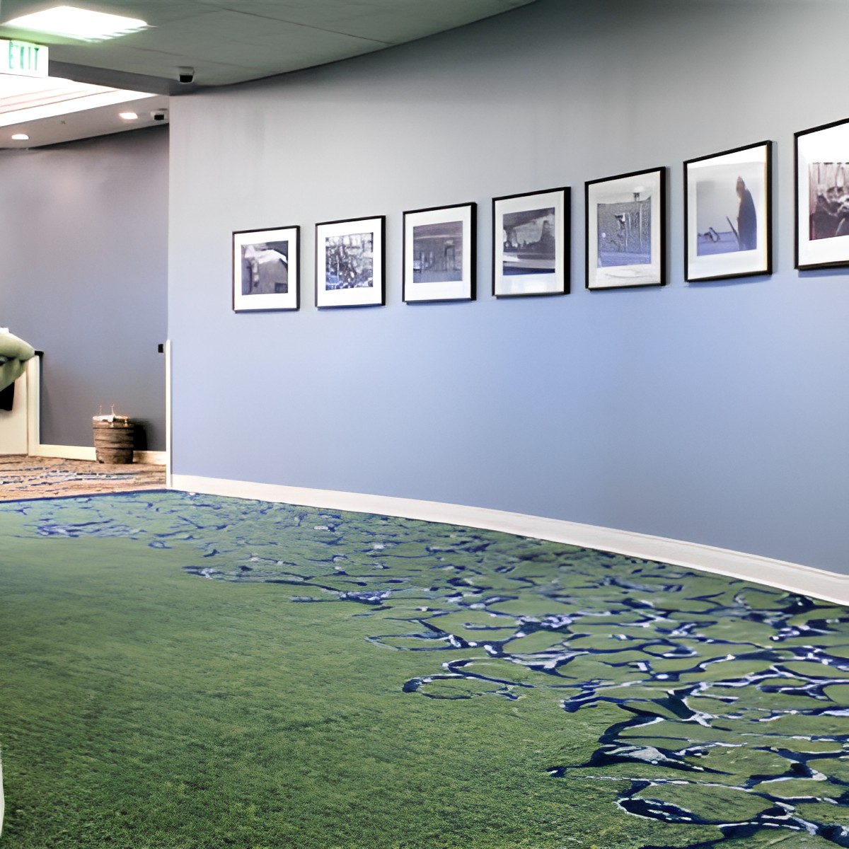 A curved hallway with blue walls decorated with framed pictures and a patterned carpet.