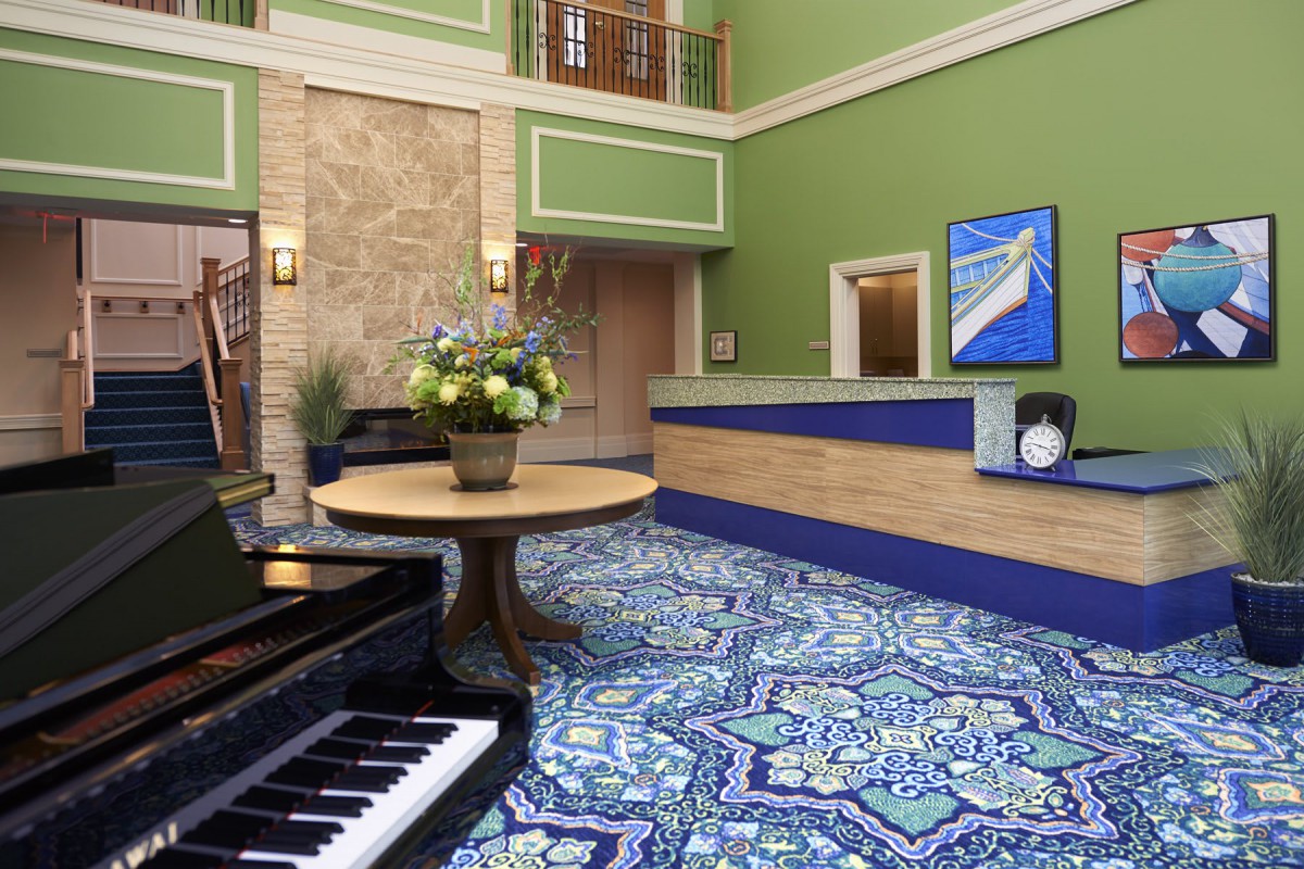 A stylish lobby featuring a piano, reception desk, and decorative elements.
