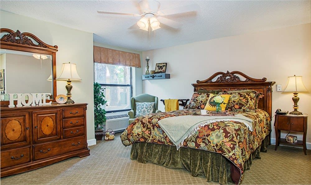 A traditional bedroom with a wooden bed, patterned bedding, and a ceiling fan.