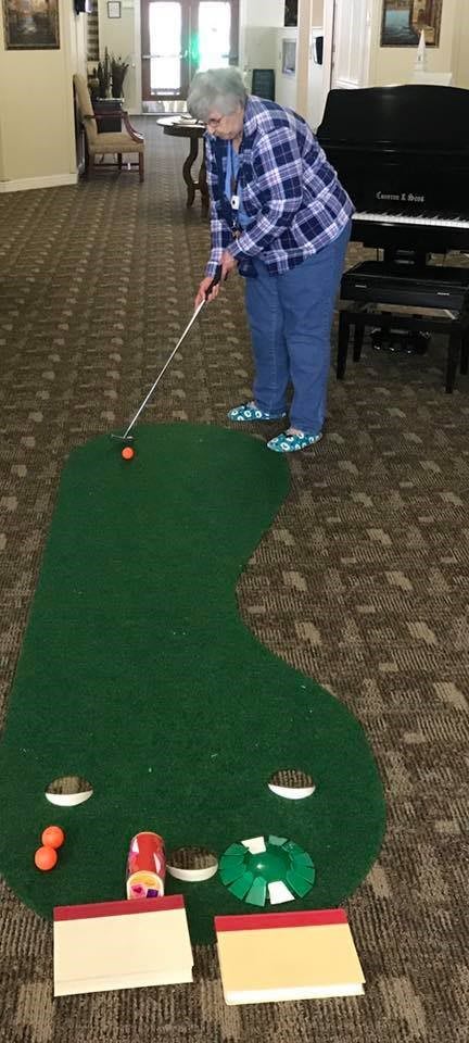 Person playing mini golf indoors on a small putting green.