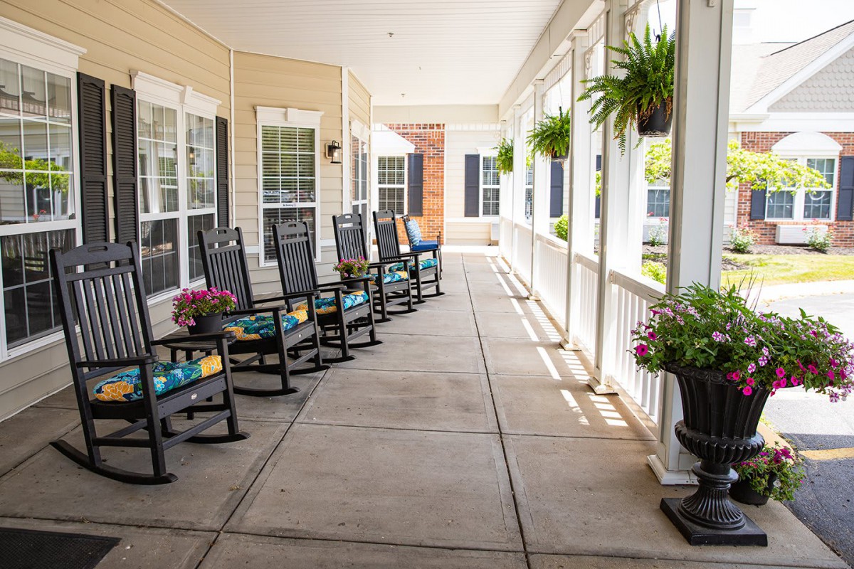 A sunny porch with rocking chairs and hanging plants.