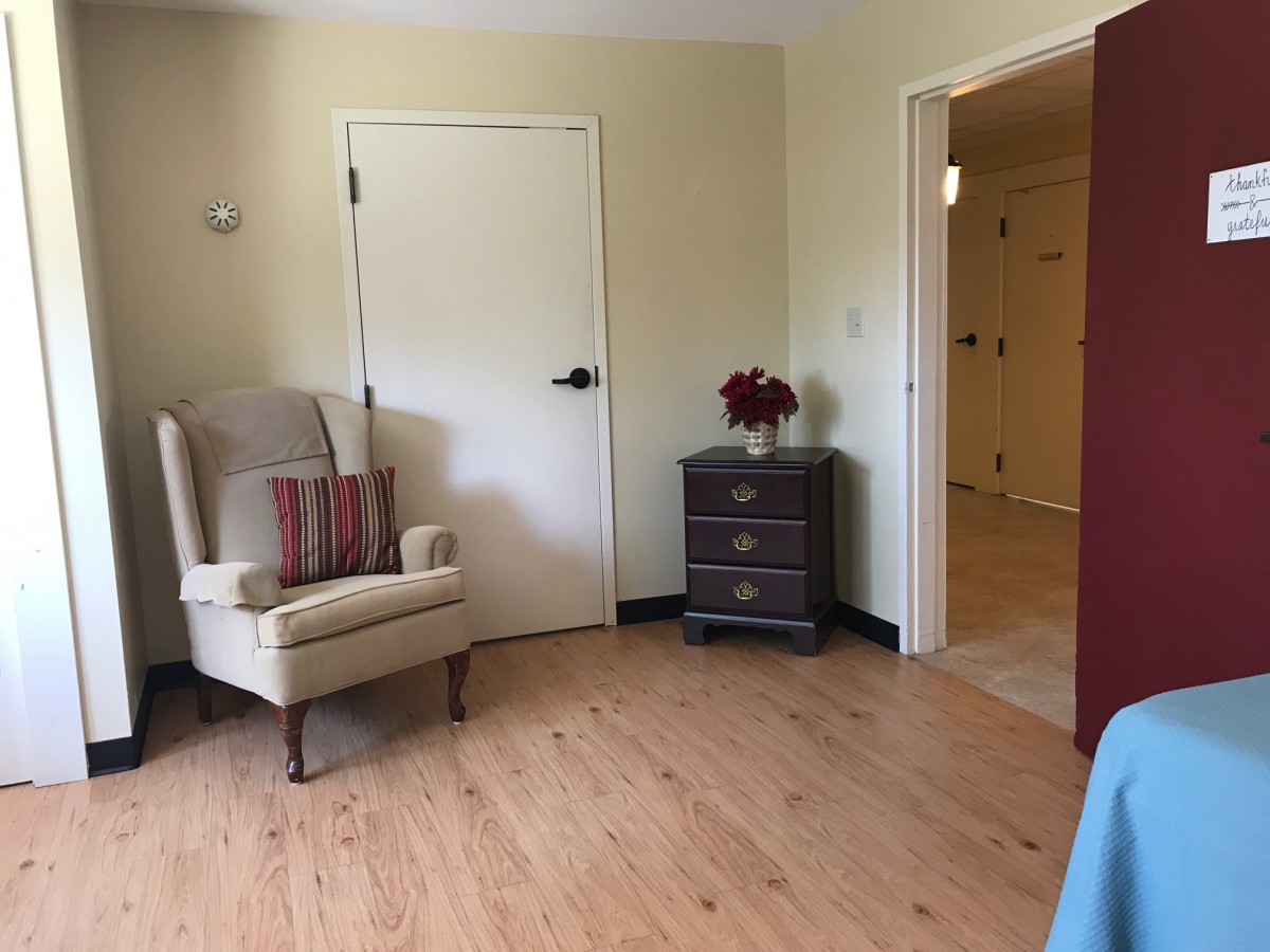 A cozy living room with an armchair, side table, and wooden flooring.