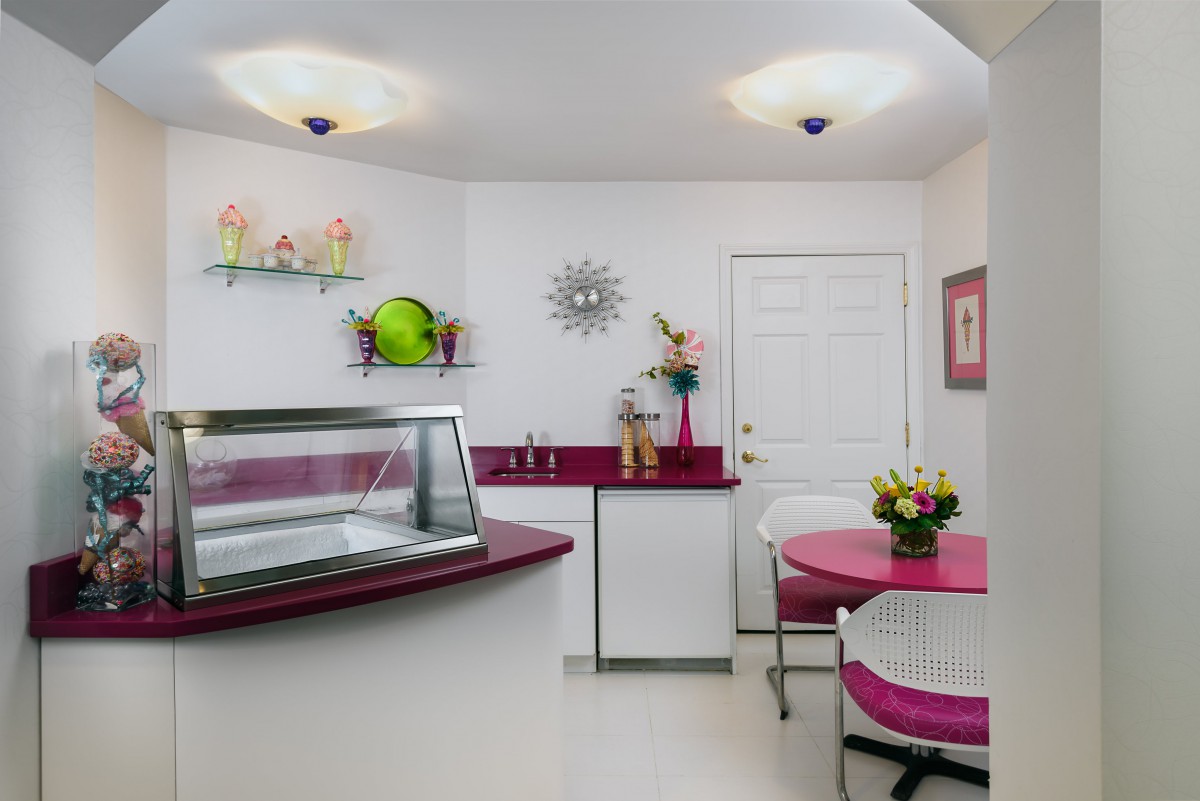 A charming retro-style ice cream shop with pink and white decor, featuring a counter and cozy seating area.