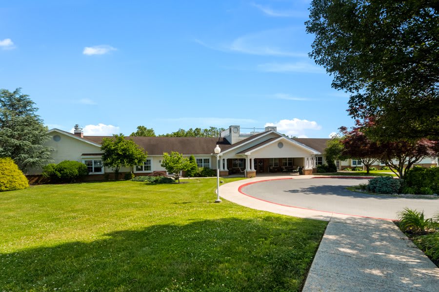 A sunny day view of a residential building with a driveway and a well-maintained lawn.