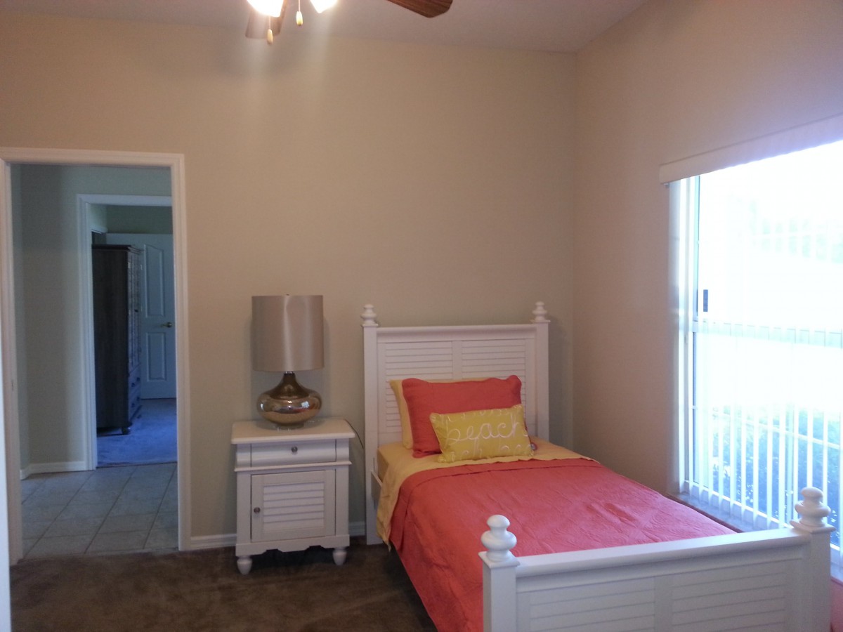 A simple bedroom with a single bed, nightstand, and window.