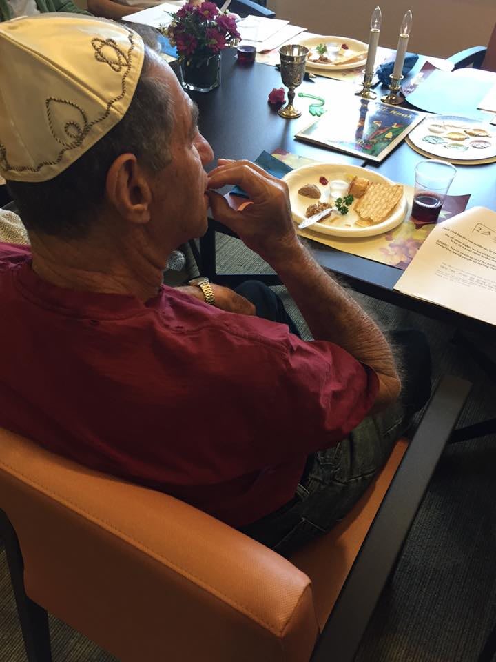 A person wearing a hat is sitting at a table with a plate of food.