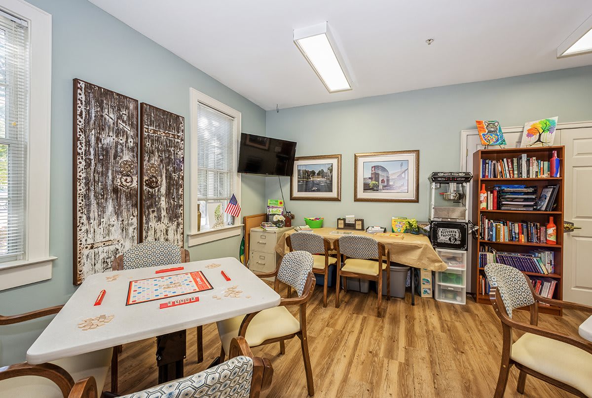 A cozy office meeting room with tables, chairs, and artwork on the walls.