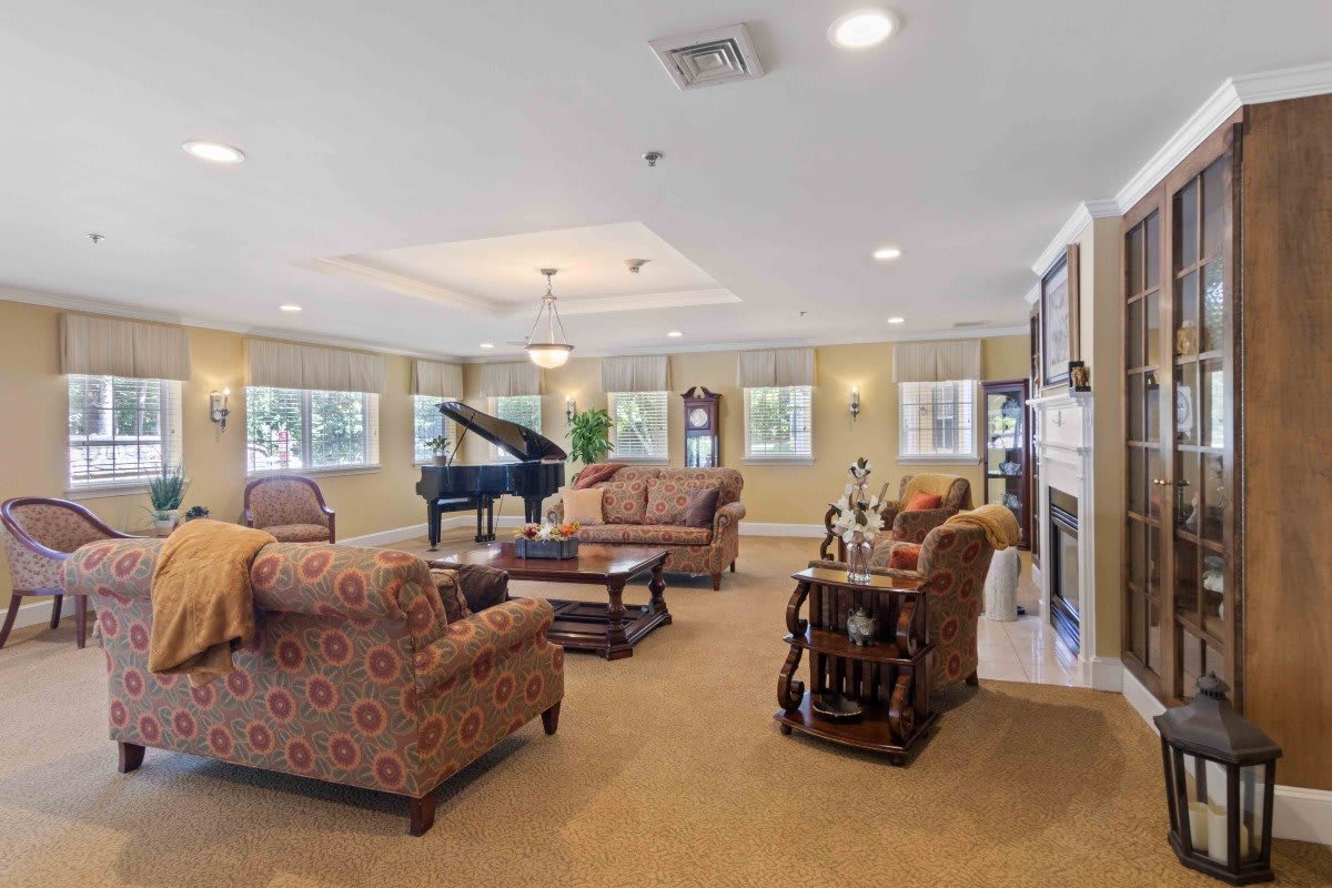 A spacious living room featuring elegant furniture, a grand piano, and a cozy fireplace.