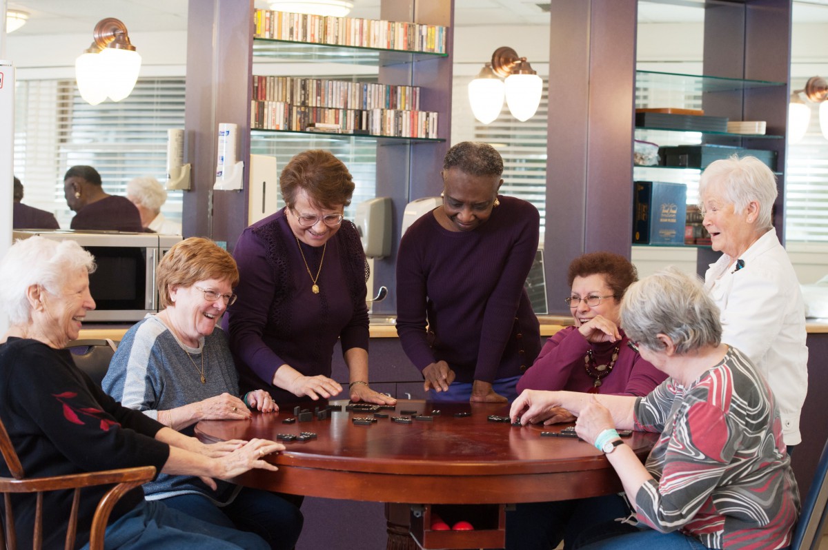 A group of seniors enjoying a gathering around a table indoors.
