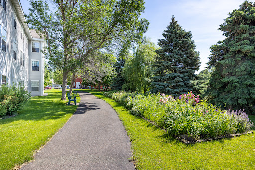 A serene walking path lined with trees and colorful flowers in a vibrant park.