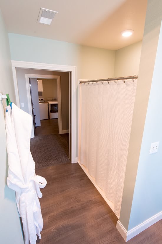 A view of a home interior showcasing a bathroom with a shower curtain and towel hanging on the wall, leading into a hallway.