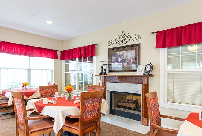 A cozy dining room with a decorated fireplace and elegant table settings.