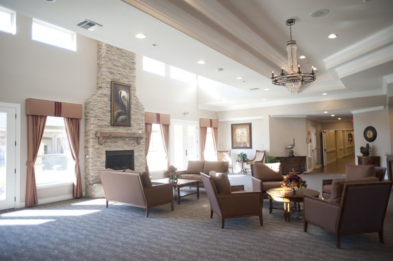 A spacious and elegantly decorated living room with a fireplace, multiple seating areas, and large windows providing natural light.