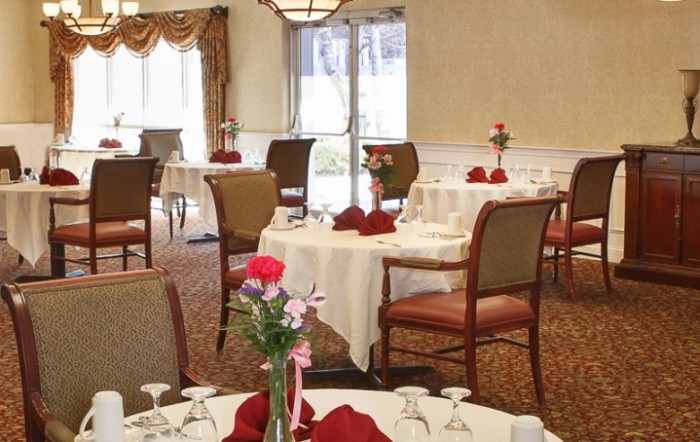 An elegant dining room with tables set for a meal, decorated with flowers and napkins.