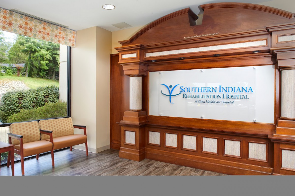 The reception area of a hospital lobby featuring wooden accents and a sign for Southern Indiana Rehab Hospital.