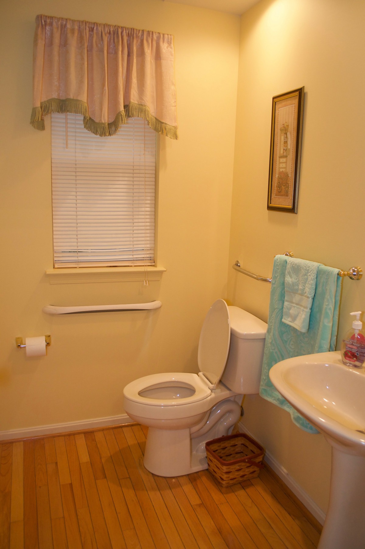 A small bathroom with a toilet, sink, and teal towels.