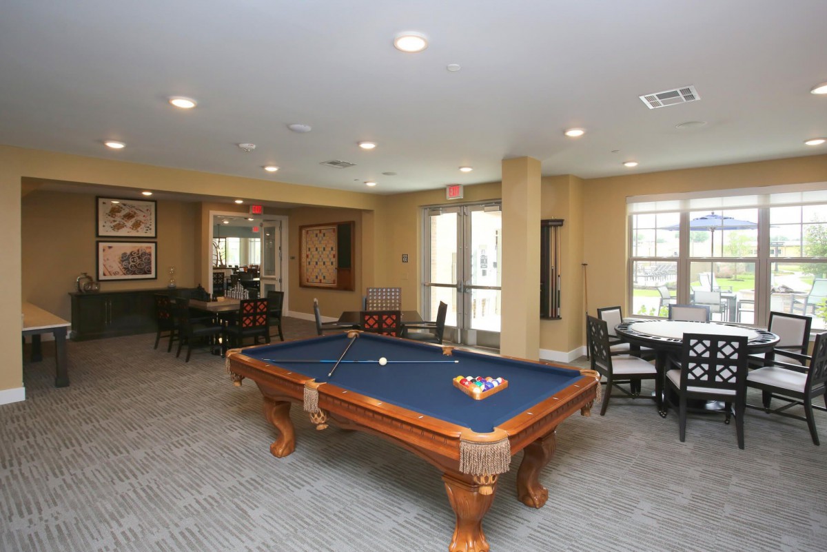 A recreation room featuring a pool table and seating areas.