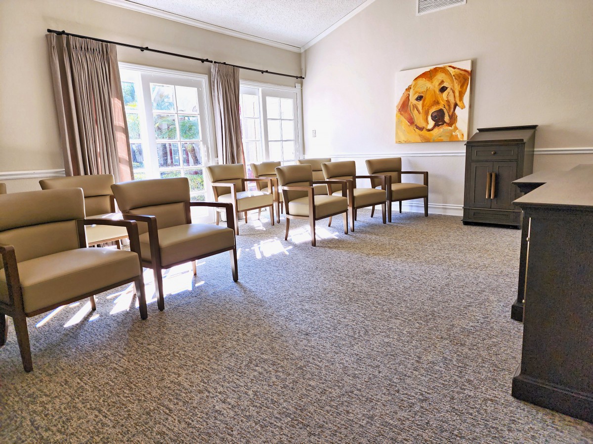 A well-lit waiting room with rows of chairs and a colorful artwork on the wall.