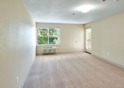 An empty apartment living room with natural light coming through a window.