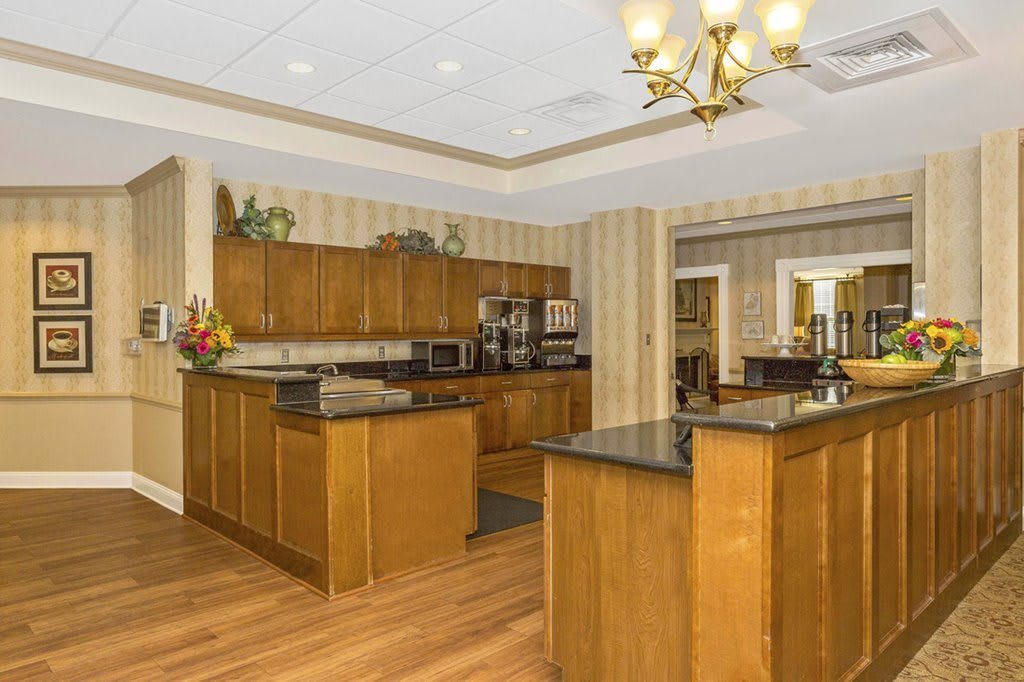 A spacious kitchen with wooden cabinets, a central island, and a chandelier.