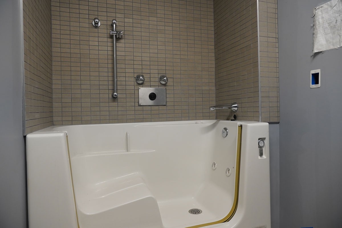 A walk-in bathtub in a modern, tiled bathroom designed for accessibility.