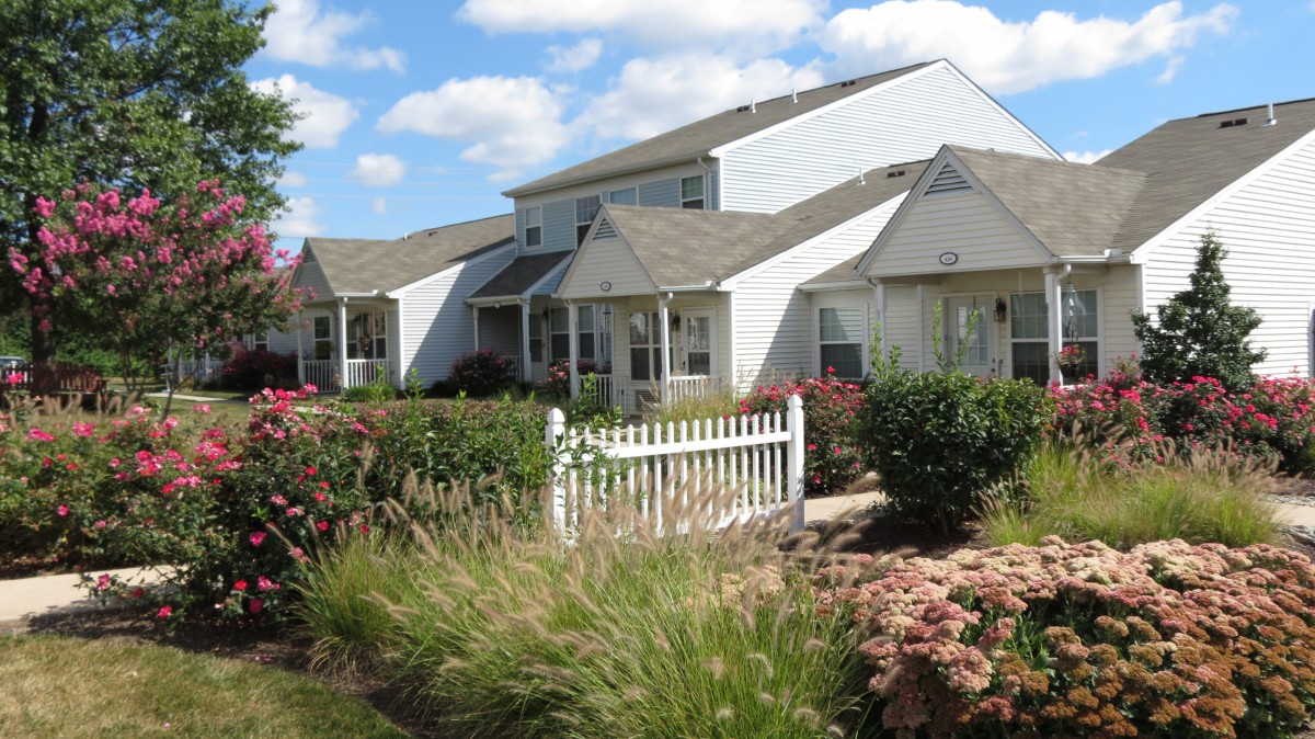 A suburban house with a well-maintained garden and white picket fence.