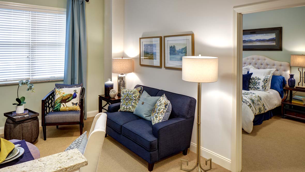 A cozy living room with a dark blue sofa, decorative pillows, and elegant lighting.