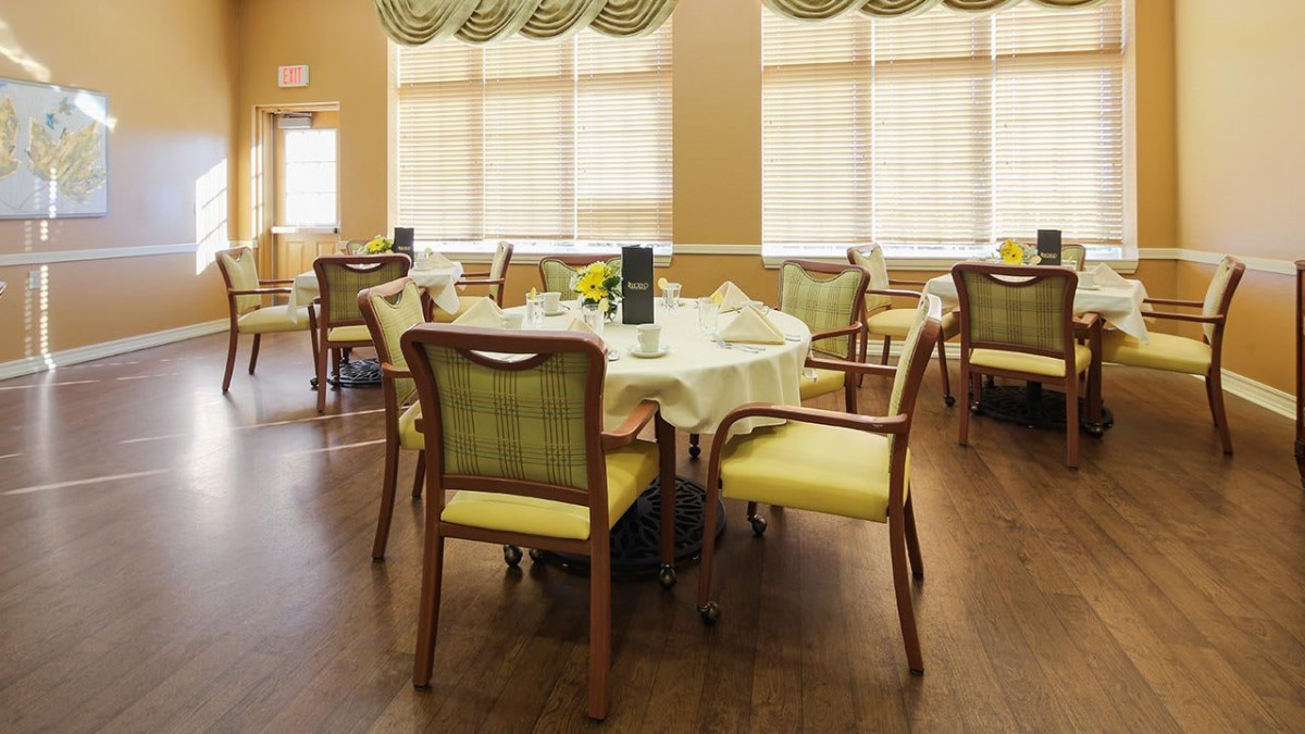 An elegantly decorated dining area with several round tables and upholstered chairs.