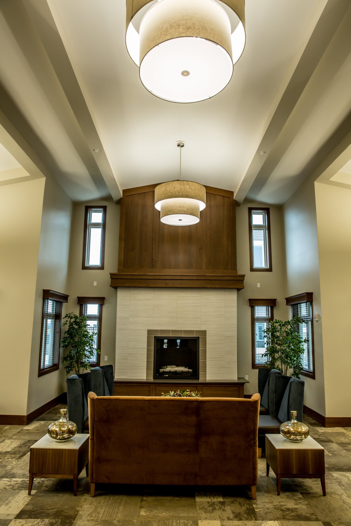 A modern living room with a high ceiling, featuring a central fireplace and contemporary decor.