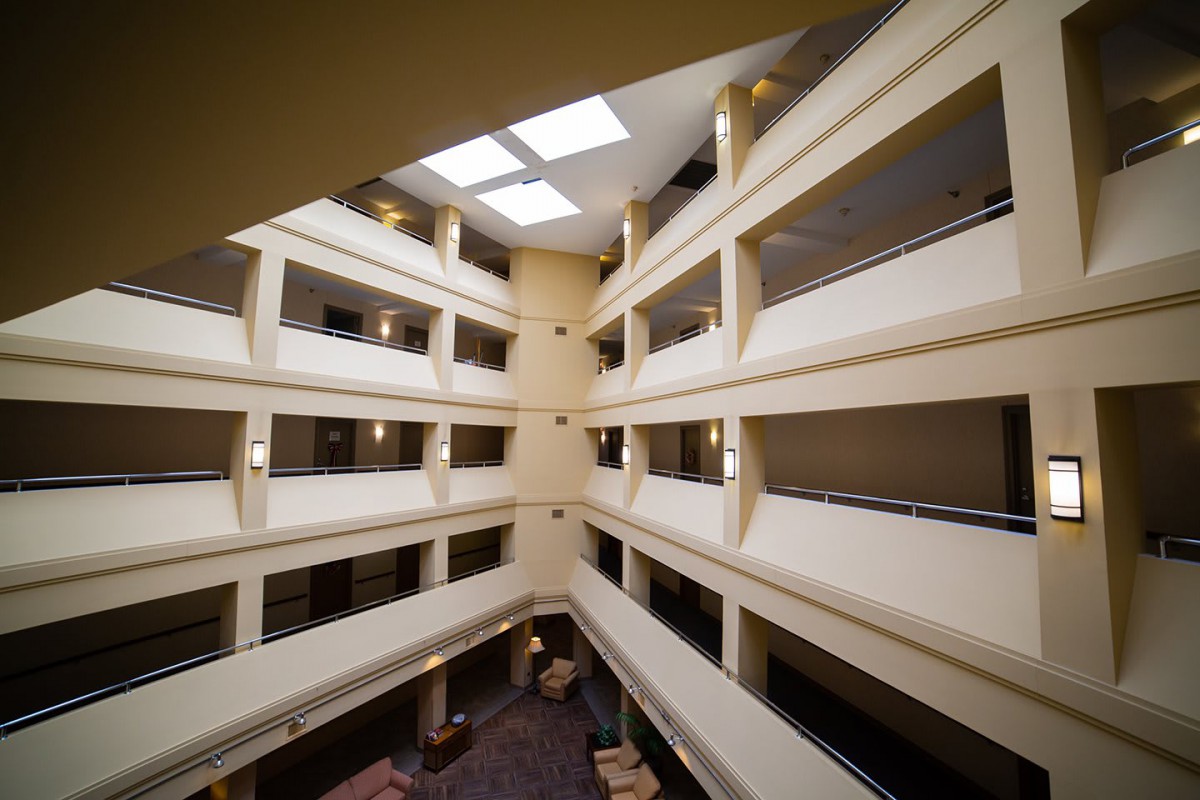 A symmetrical view of an atrium with multiple floors and balconies, topped by a skylight.