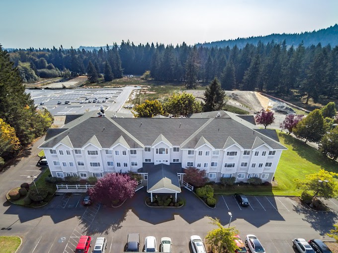 Aerial view of a large residential building with a parking lot surrounded by trees.