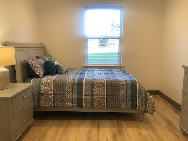 A cozy bedroom with a neatly made bed and a window letting in natural light.