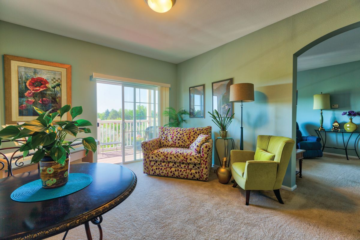 A cozy living room with colorful furniture and natural lighting from a large window.