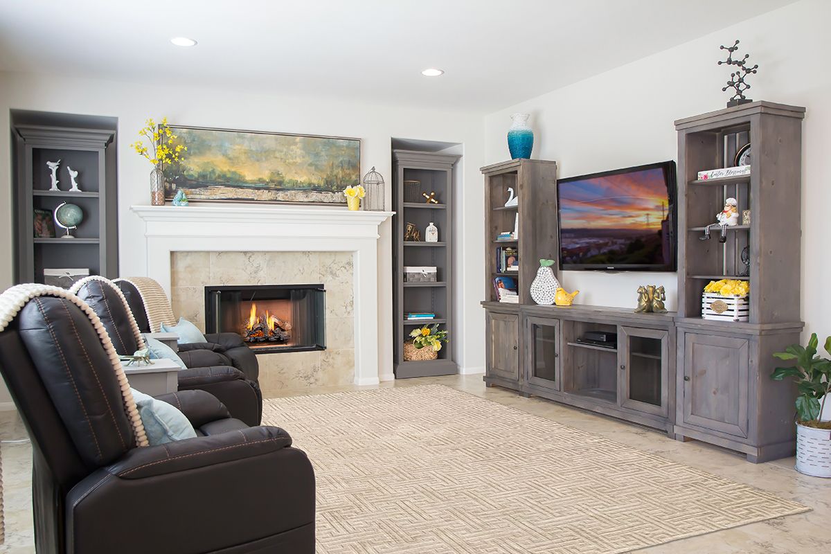 A cozy living room with a fireplace and TV, surrounded by comfortable seating and decorative shelves.
