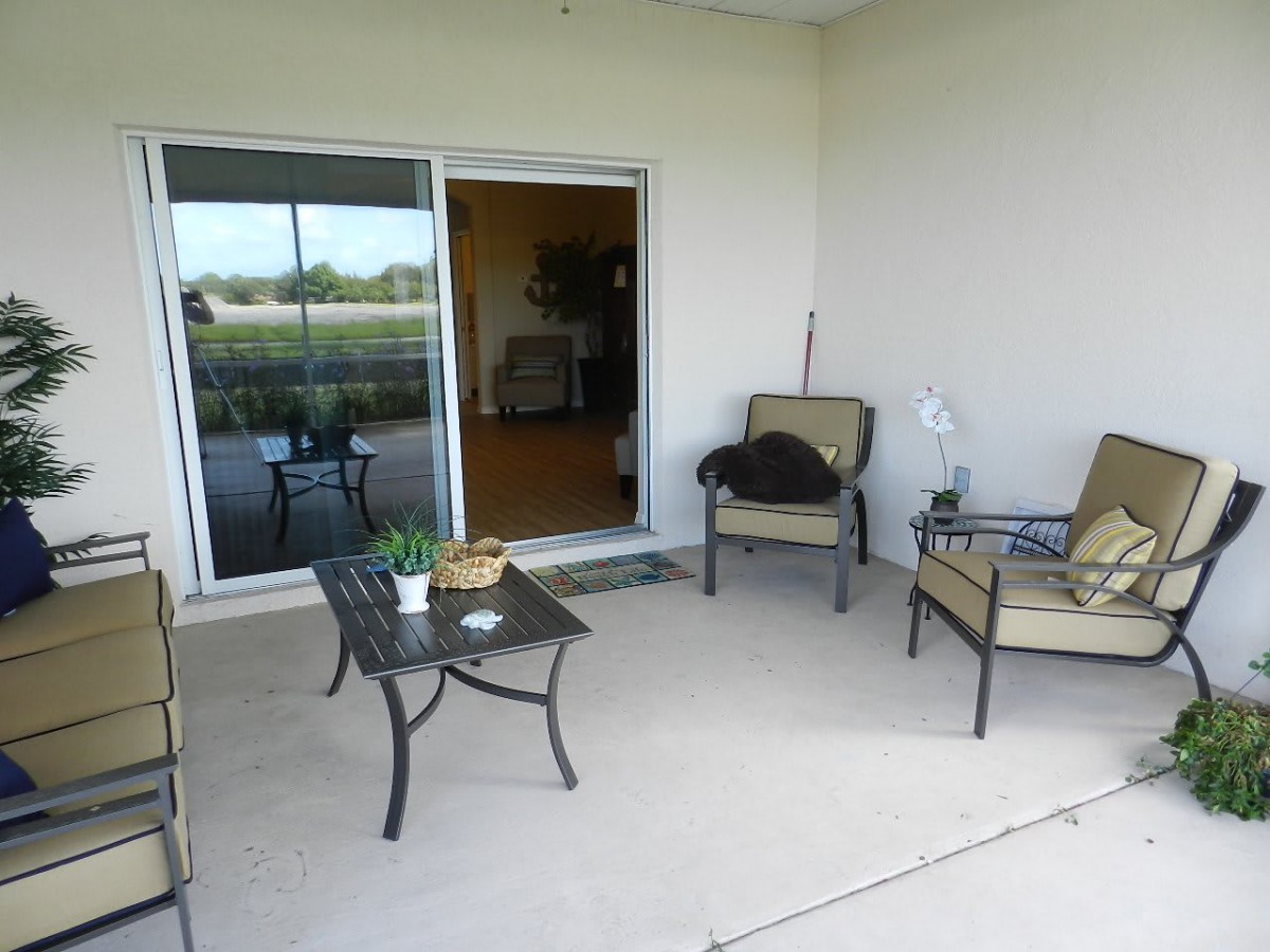 A cozy patio area with outdoor seating and a table, connected to the indoors by a sliding door.
