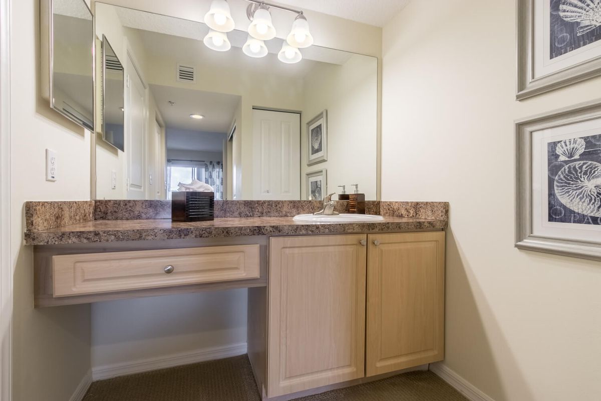 A bathroom vanity with a large mirror and overhead lighting.