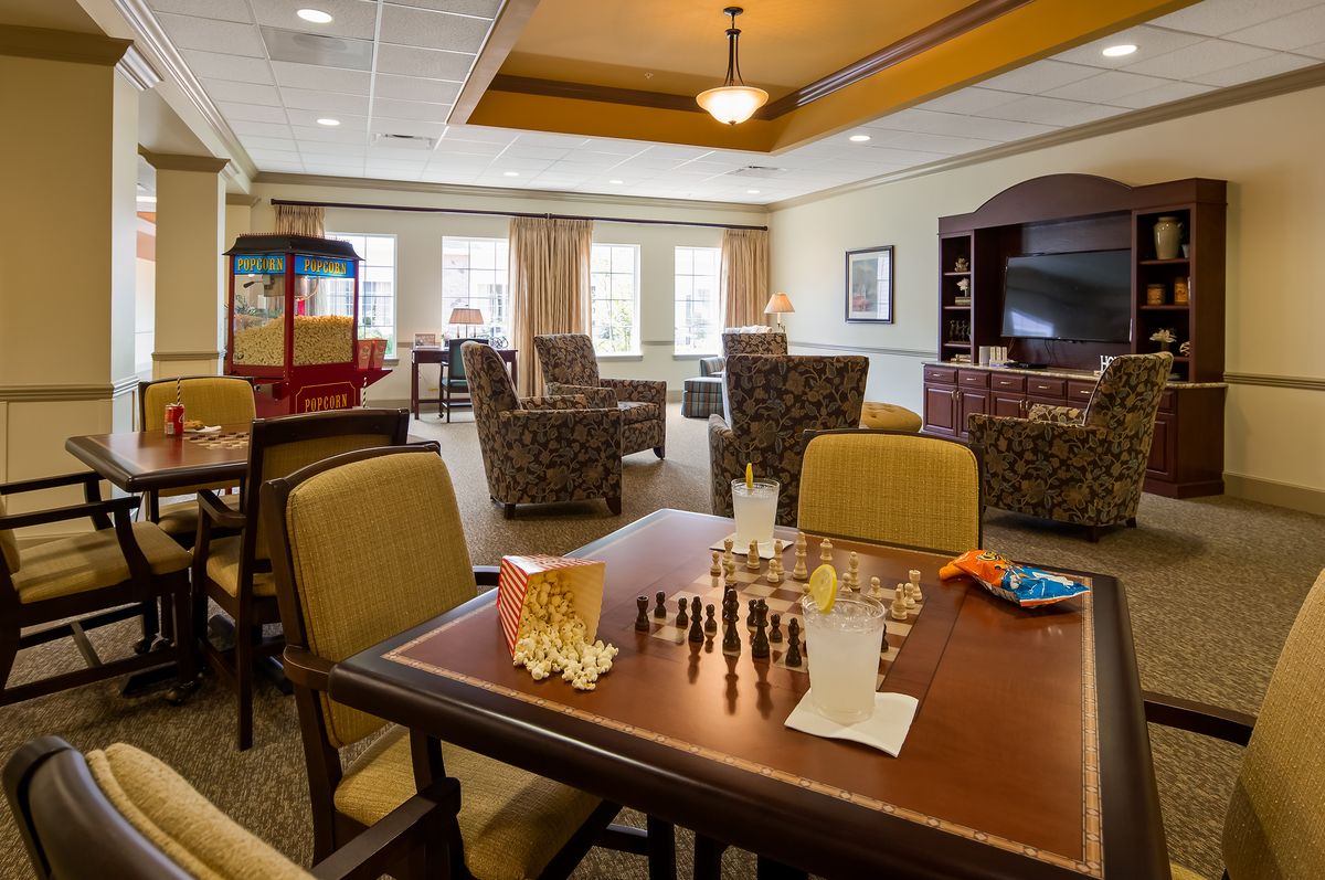A cozy living room with a chess board on the table, surrounded by comfortable seating and a popcorn machine in the corner.