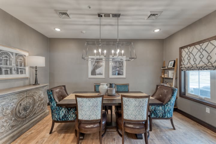A cozy dining room with a wooden table, upholstered chairs, and a decorative chandelier.